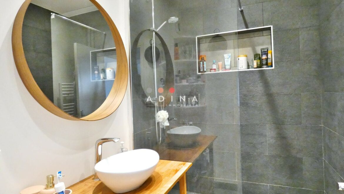 Salle de bain moderne avec douche à l'italienne et miroir rond.