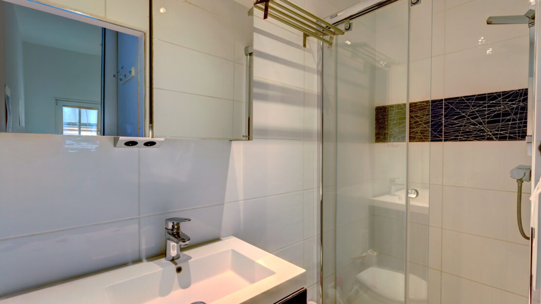 Salle de bain moderne avec douche vitrée et lavabo.