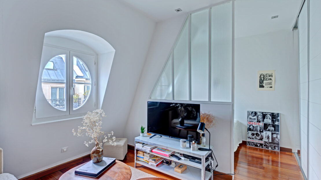 Salon moderne avec fenêtre ronde et parquet en bois.