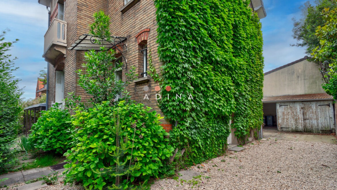 Façade en brique avec lierre et jardin gravillonné.