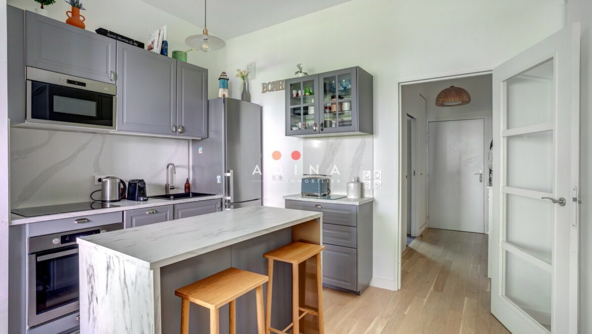 Cuisine moderne avec meubles gris et îlot central.