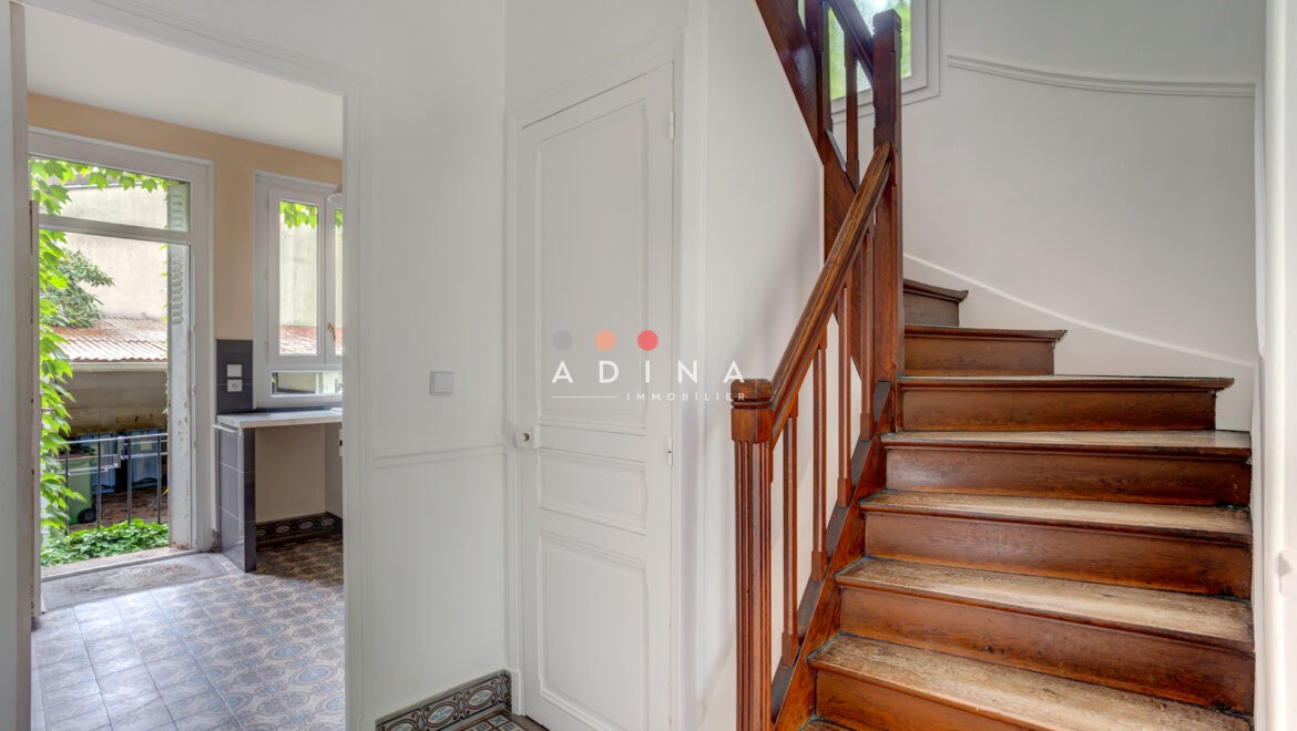 Escalier en bois dans une entrée lumineuse avec carrelage décoratif à Sceaux.