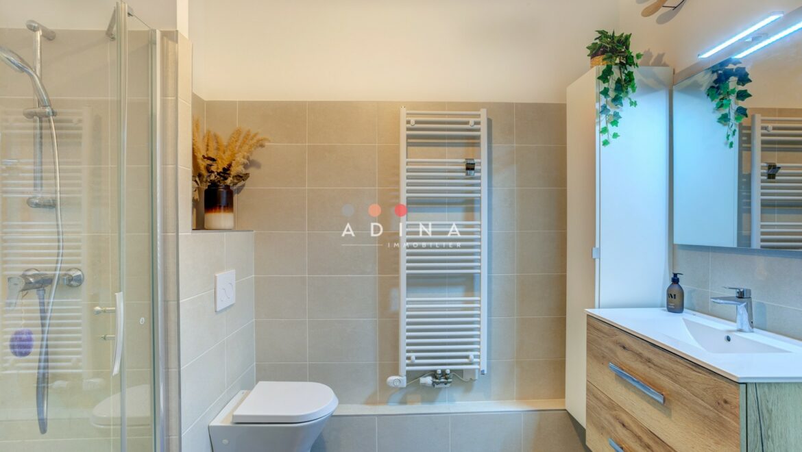 Salle de bain moderne avec douche et miroir.