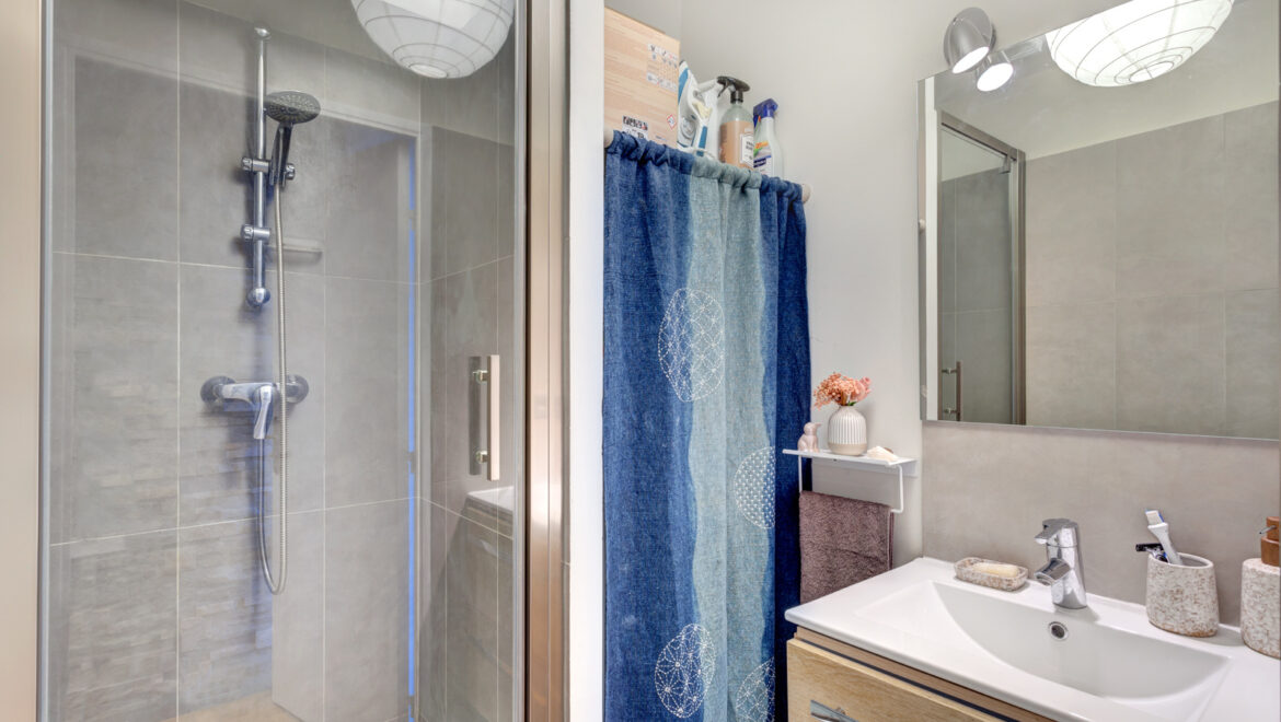 Salle de bains moderne avec douche et lavabo.