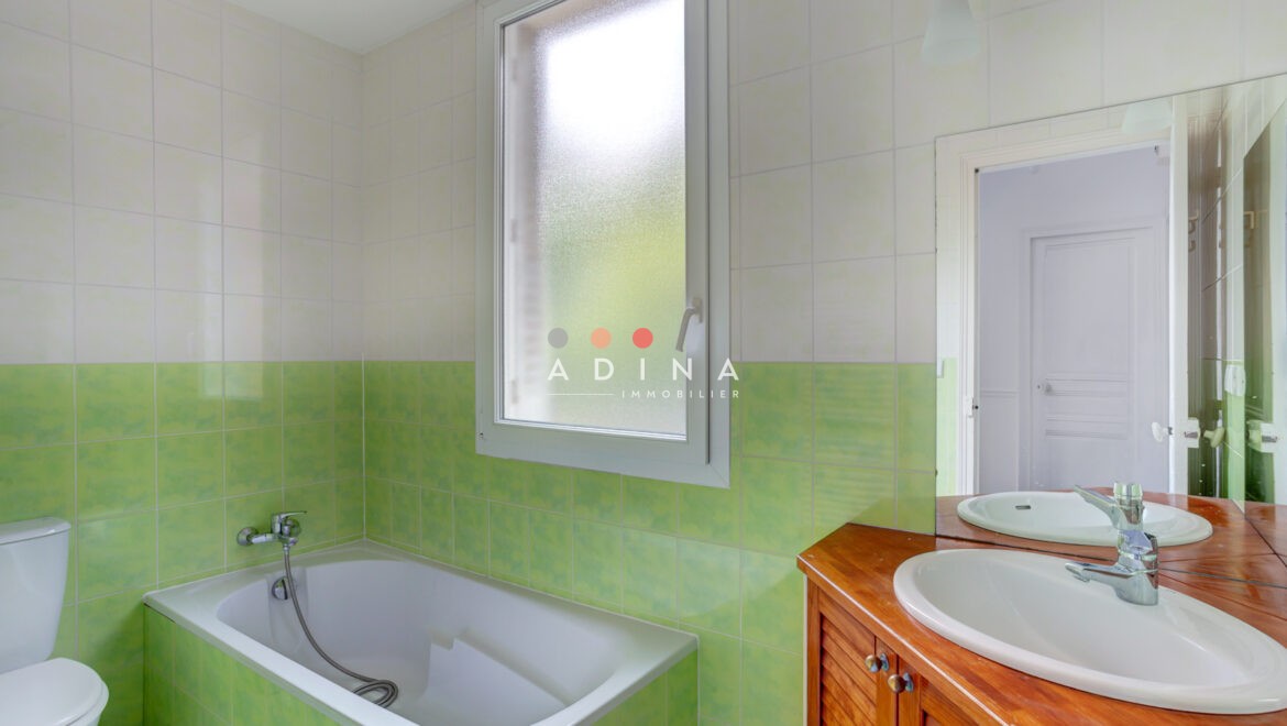 Salle de bains avec carrelage vert, baignoire et lavabo.
