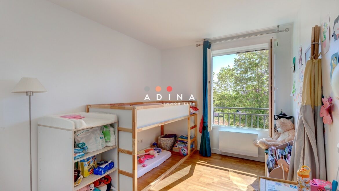 Chambre d'enfant ensoleillée avec lit superposé et vue sur jardin.