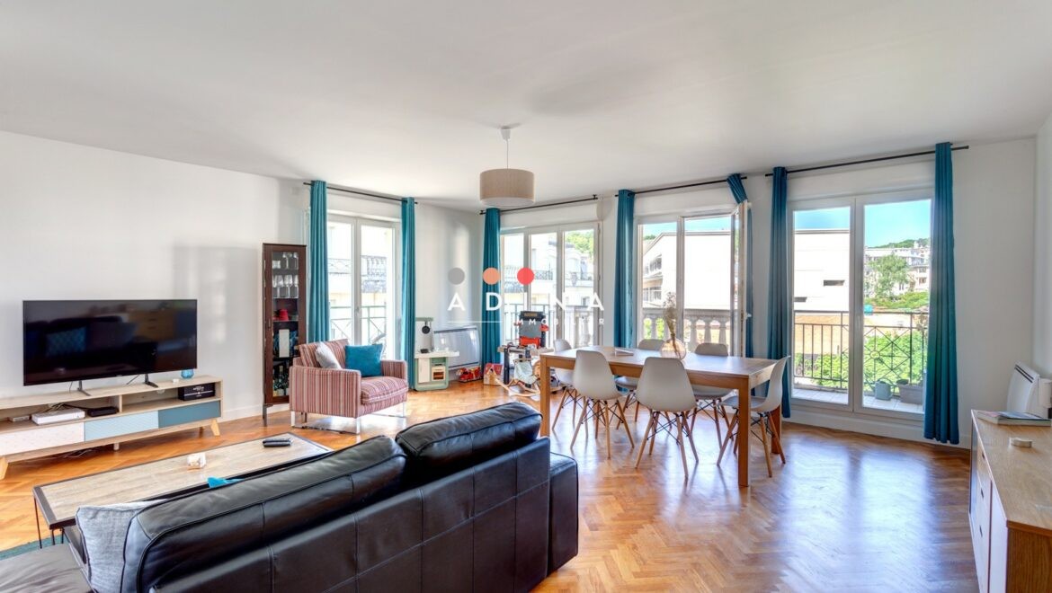Intérieur lumineux d'un salon avec parquet et grandes fenêtres.