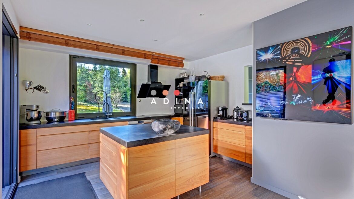 Cuisine moderne avec îlot central et vue sur jardin.