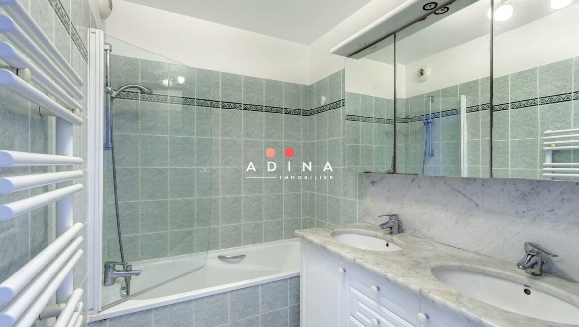 Salle de bain moderne avec double vasque et baignoire.