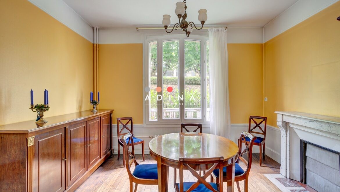 Salle à manger lumineuse avec murs jaunes et mobilier en bois à Sceaux.