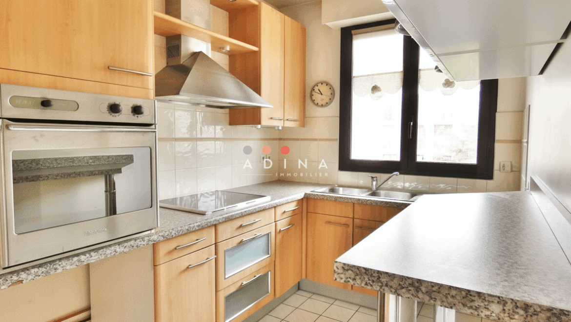 Cuisine moderne avec meubles en bois et électroménager en acier inoxydable.