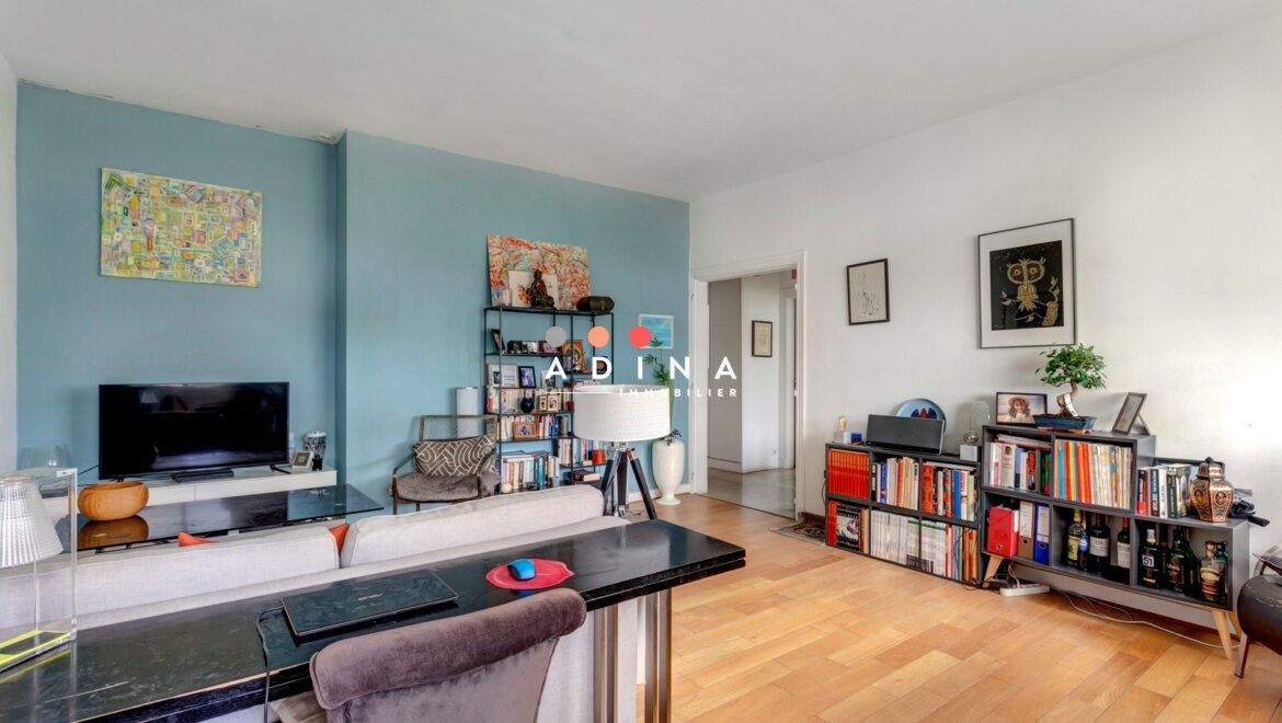 Salon moderne avec mobilier élégant et étagères remplies de livres.
