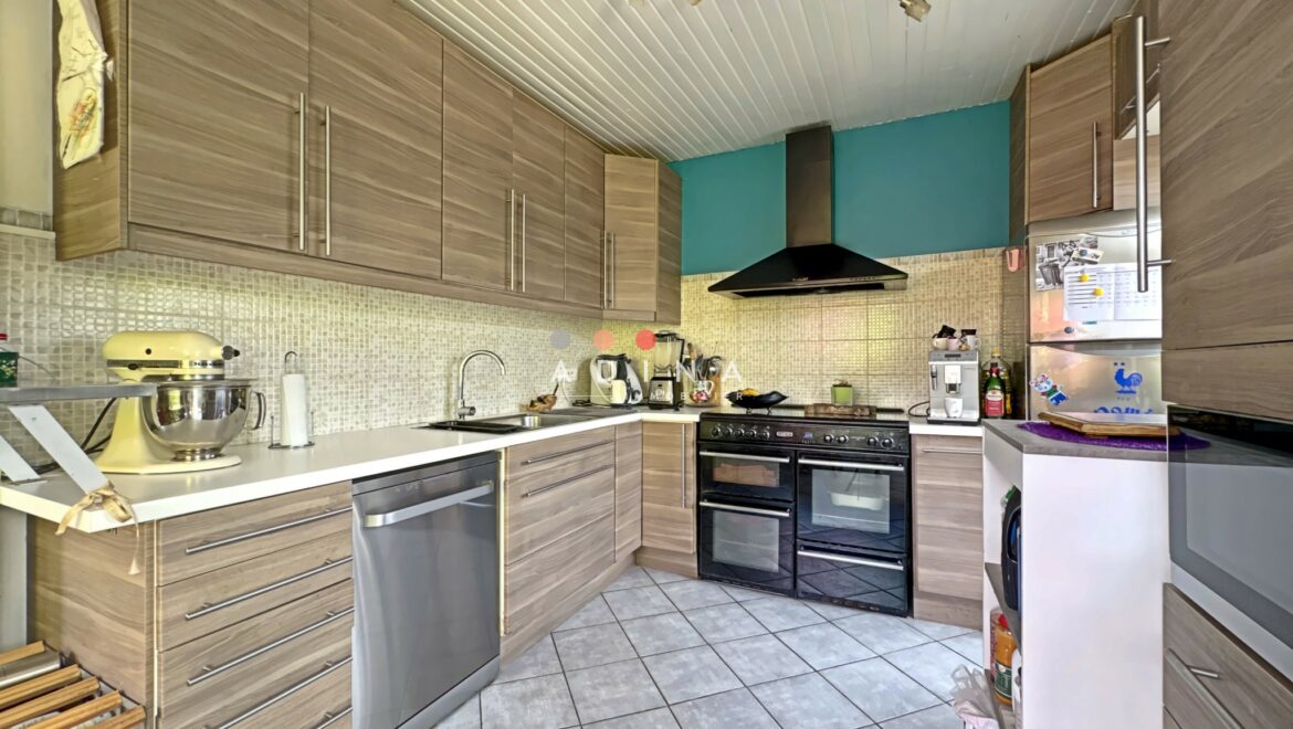 Cuisine moderne avec meubles en bois et électroménager inoxydable.