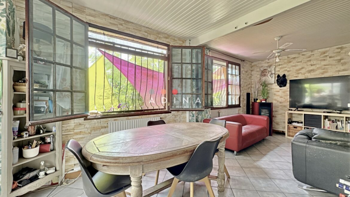 Salon lumineux avec grandes fenêtres et mobilier moderne.