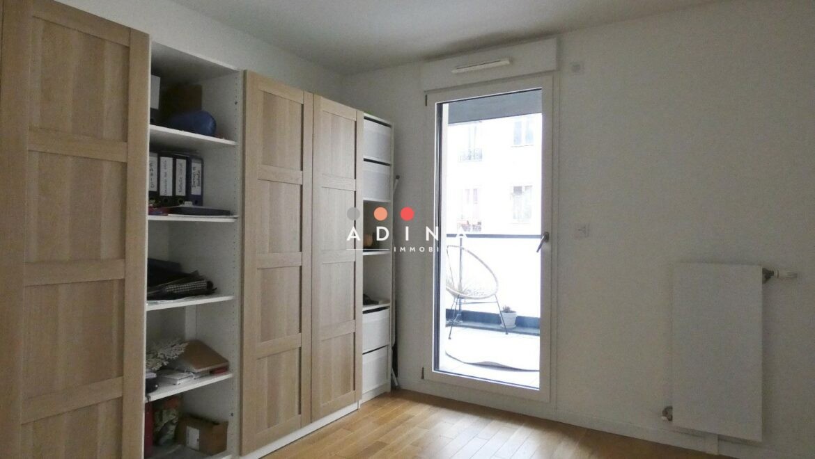 Une pièce avec parquet, placards et une fenêtre donnant sur un balcon.