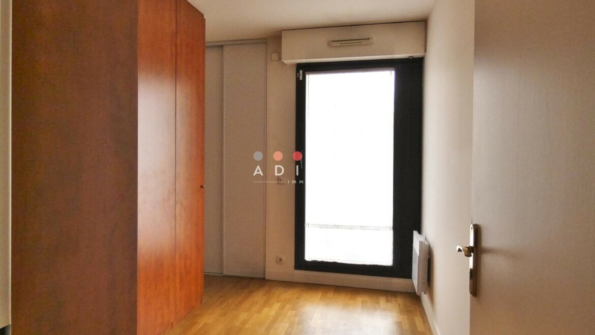 Chambre vide avec parquet et placard intégré.