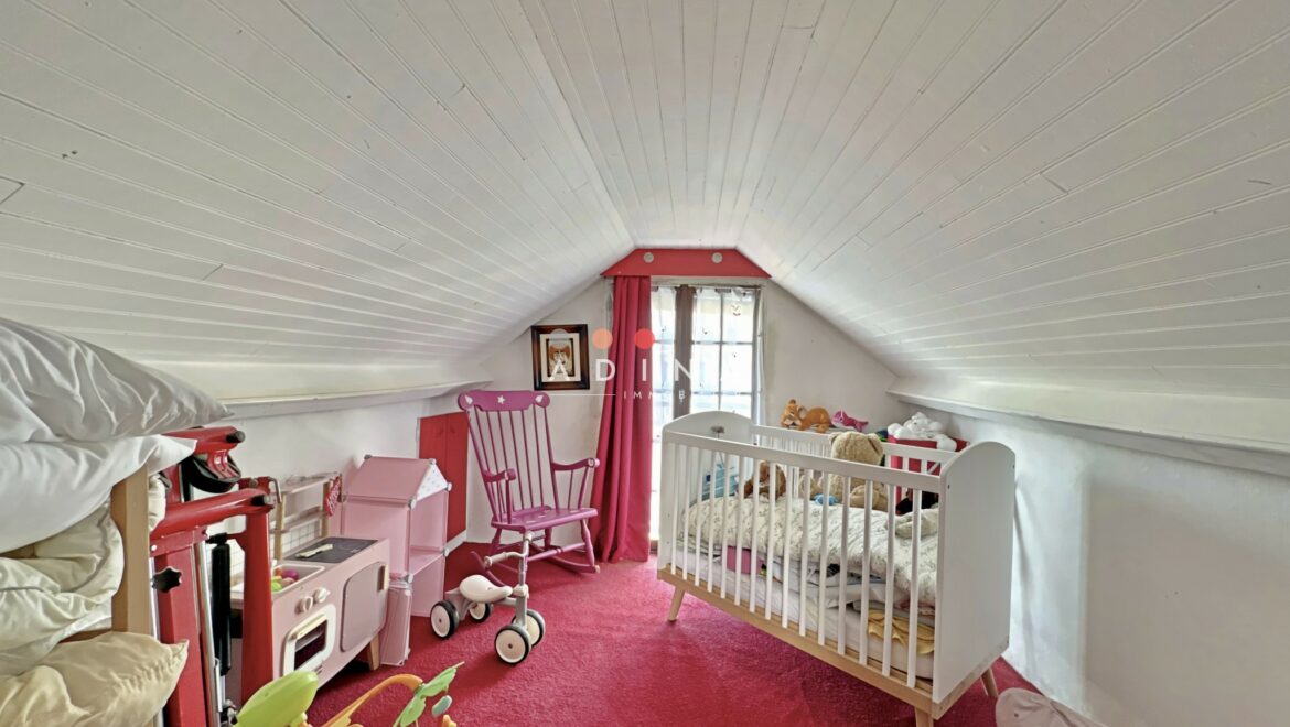 Chambre mansardée avec lit bébé et jouets.