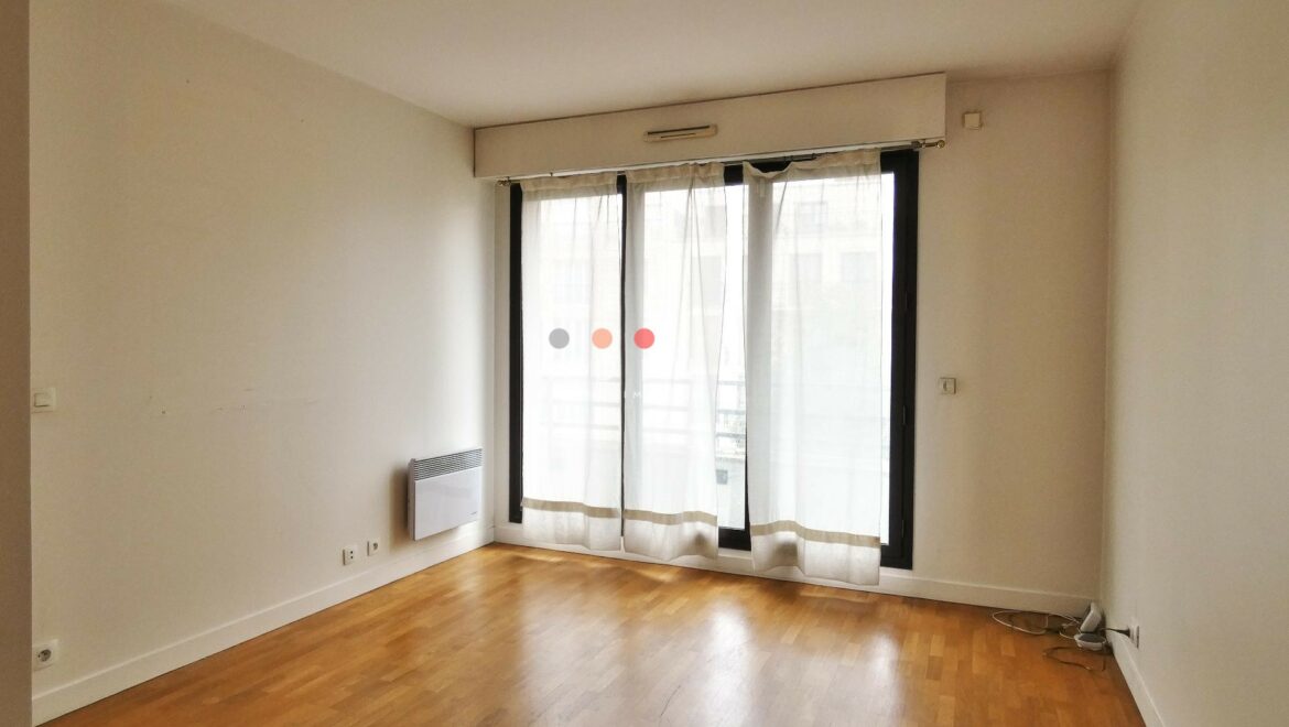 Chambre vide avec parquet et grande fenêtre.