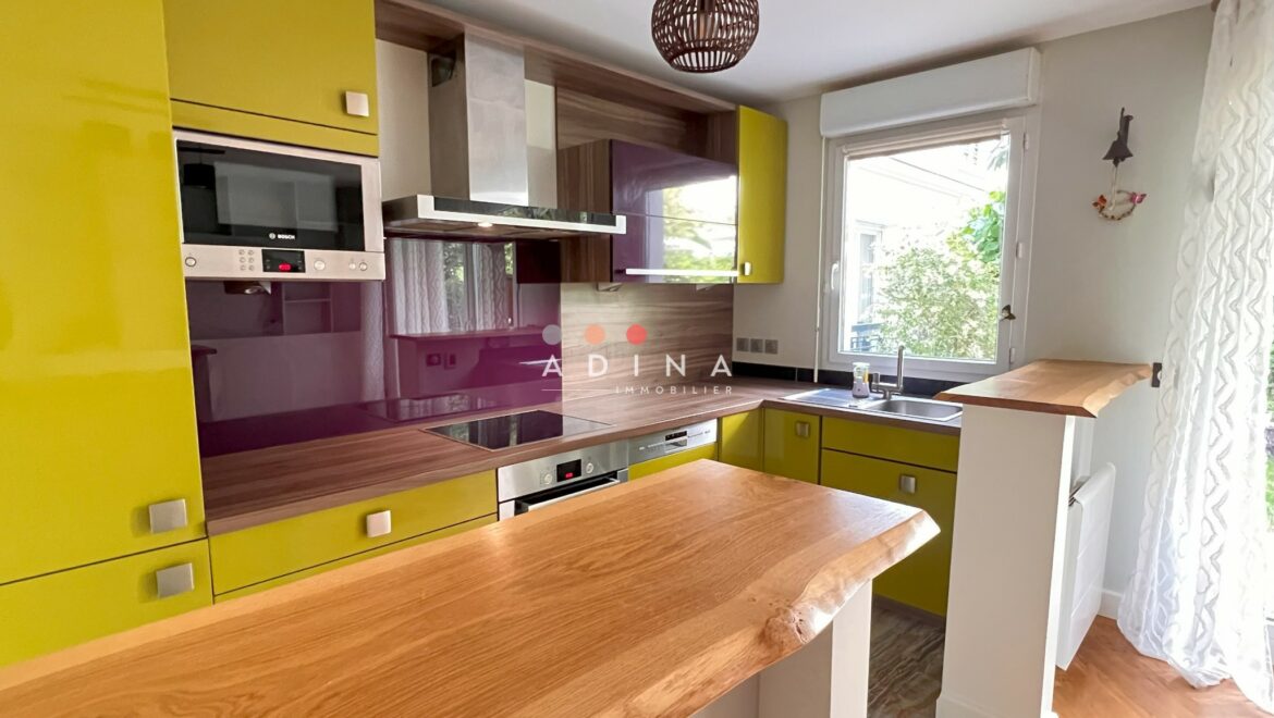 Cuisine moderne avec des meubles verts et un plan de travail en bois.