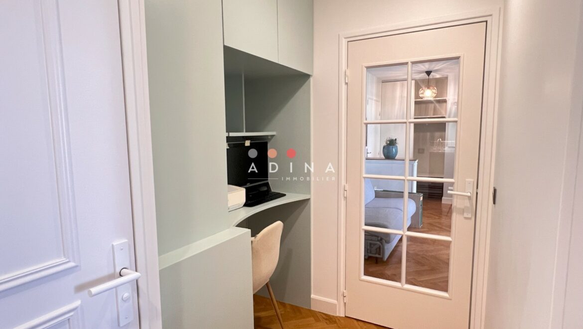 Petit espace de travail avec bureau intégré et porte vitrée.