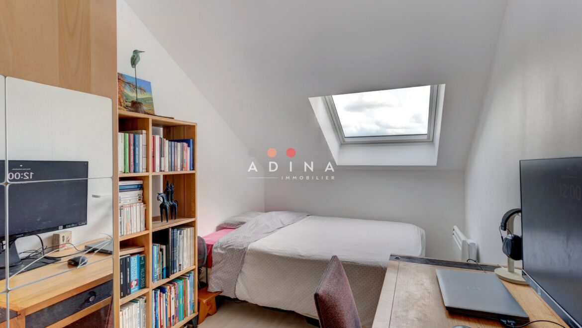 Petite chambre mansardée avec bureau et étagère à livres.