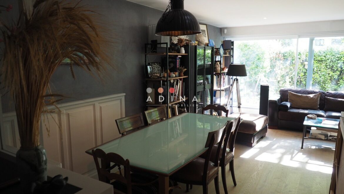 Salle à manger et salon éclairés avec vue sur le jardin.