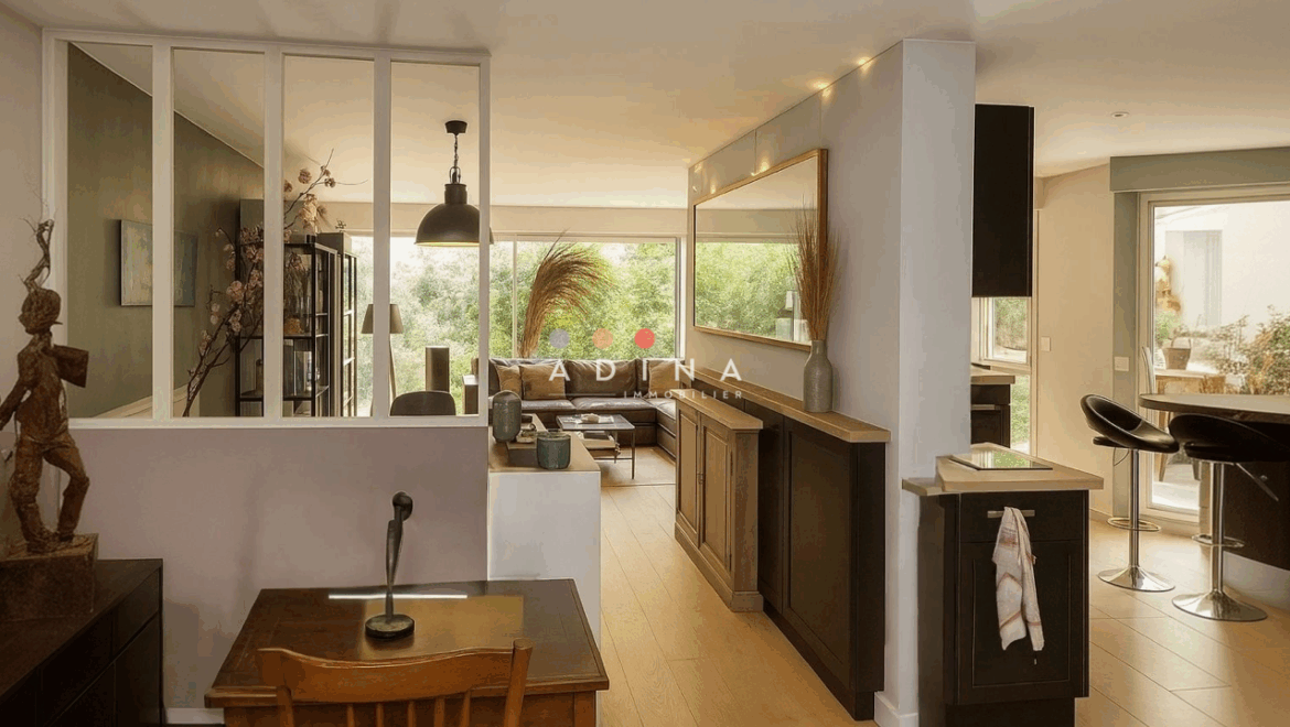 Salon moderne avec grande baie vitrée et décoration élégante.