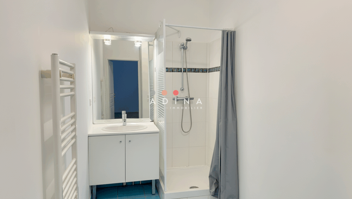 Salle de bain moderne avec douche et lavabo.