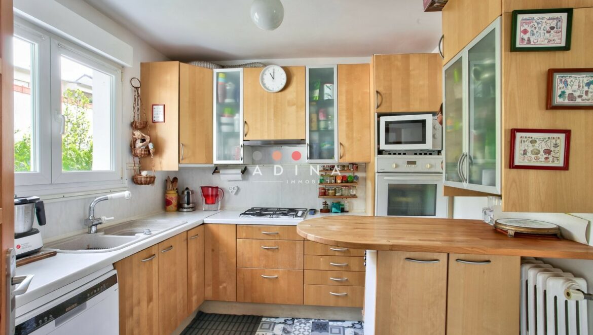 Cuisine moderne avec armoires en bois clair et appareils intégrés.