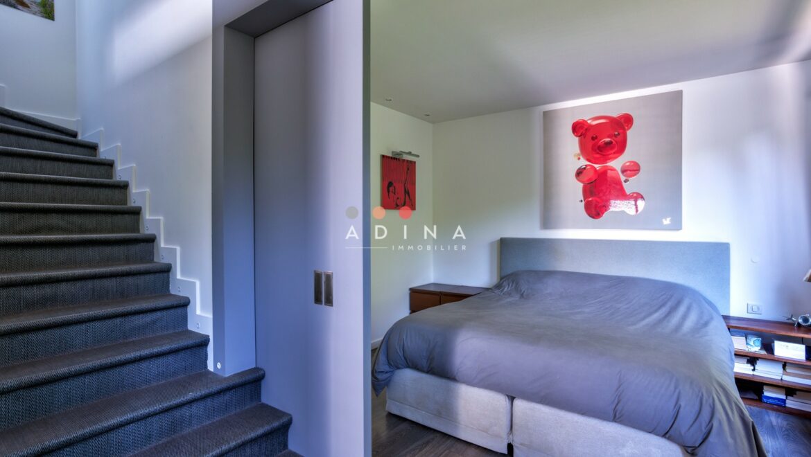Chambre moderne avec escalier et décoration murale.