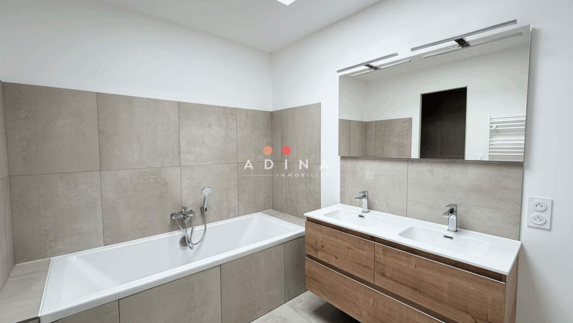 Salle de bain moderne avec baignoire et double lavabo.