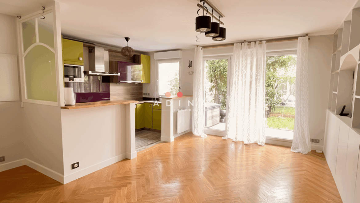 Salon moderne avec cuisine ouverte, parquet et grandes fenêtres à Le Plessis-Robinson.