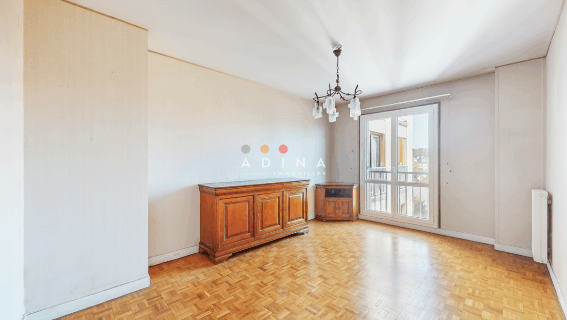 Salle à manger vide avec parquet et buffet en bois.