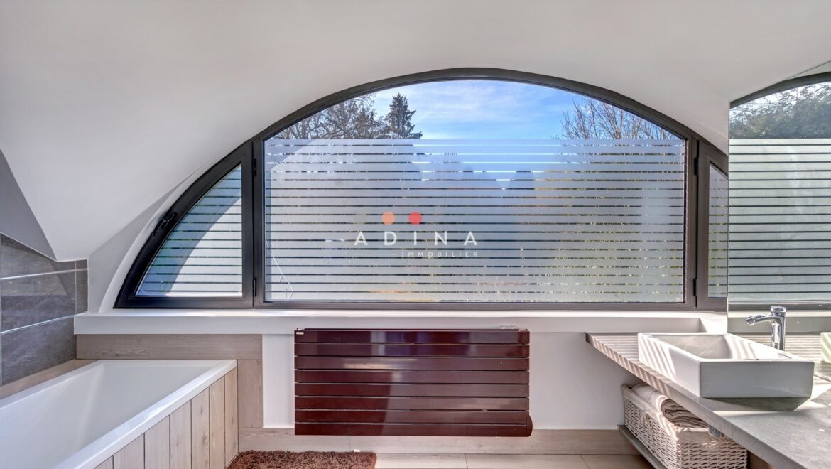 Salle de bain moderne avec grande fenêtre arquée.