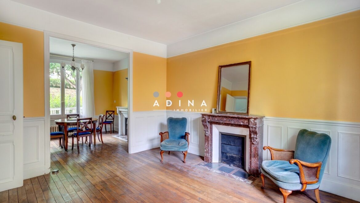 Salle de séjour avec cheminée et coin repas, parquet au sol.