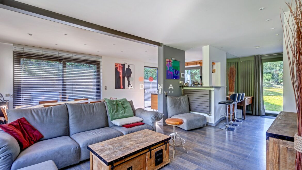 Salon moderne et spacieux avec canapé gris et table en bois.