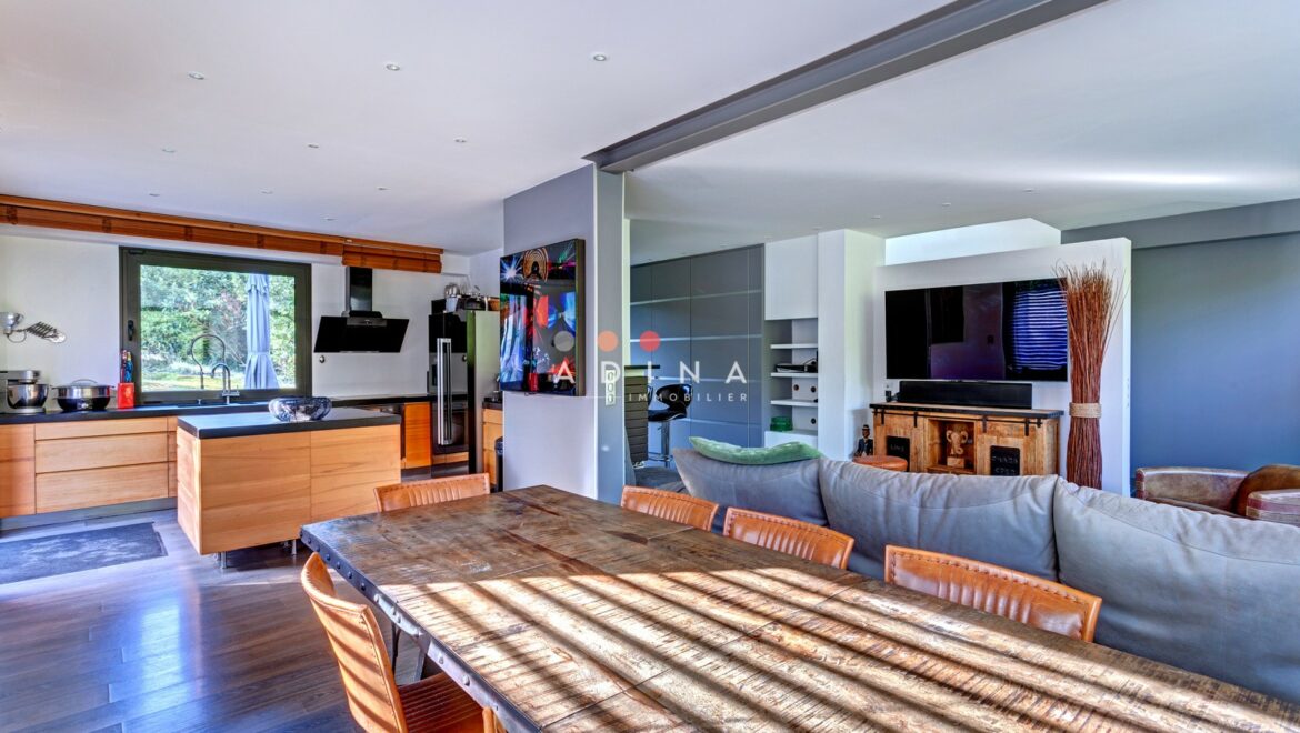 Salon avec cuisine ouverte et table à manger en bois.