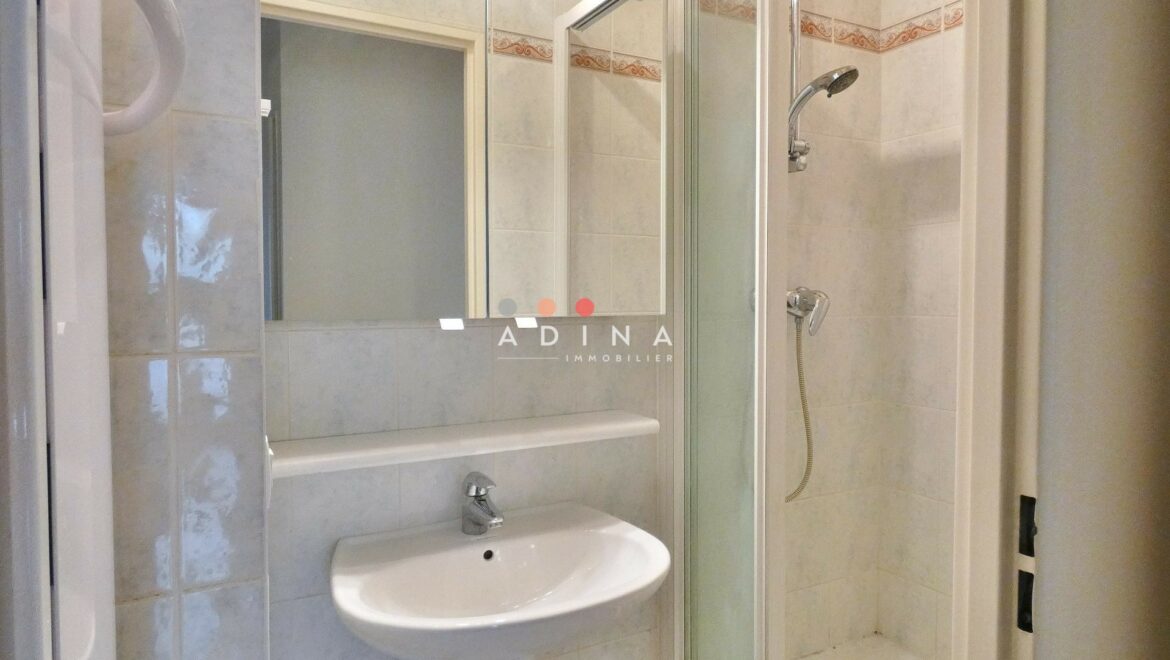 Salle de bain moderne avec douche et lavabo.