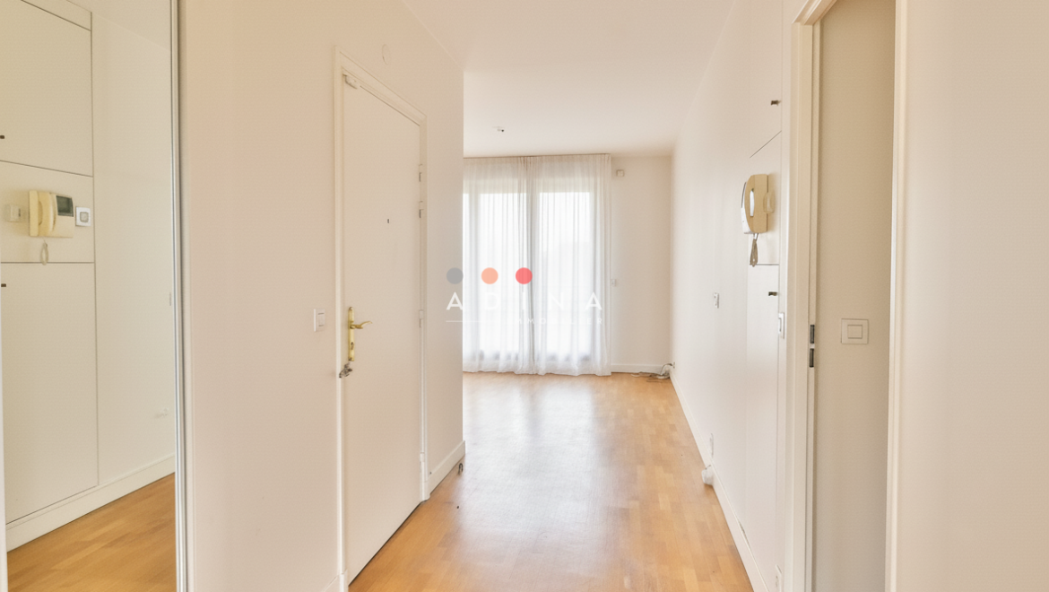 Couloir lumineux avec parquet et porte-fenêtre.