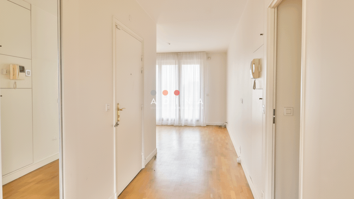 Entrée lumineuse avec parquet et baies vitrées.