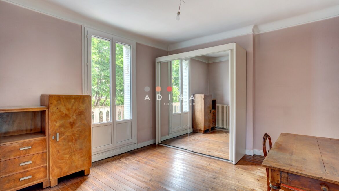 <p>Chambre lumineuse avec parquet et meubles en bois.</p>