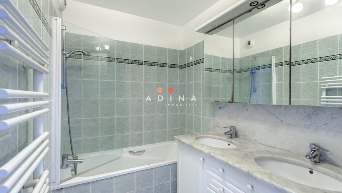 Salle de bain avec double vasque et baignoire.