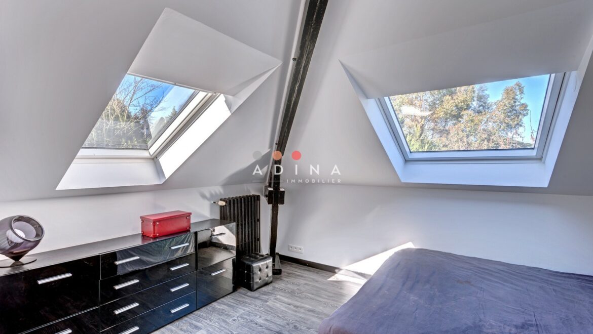 Chambre mansardée avec fenêtres de toit.