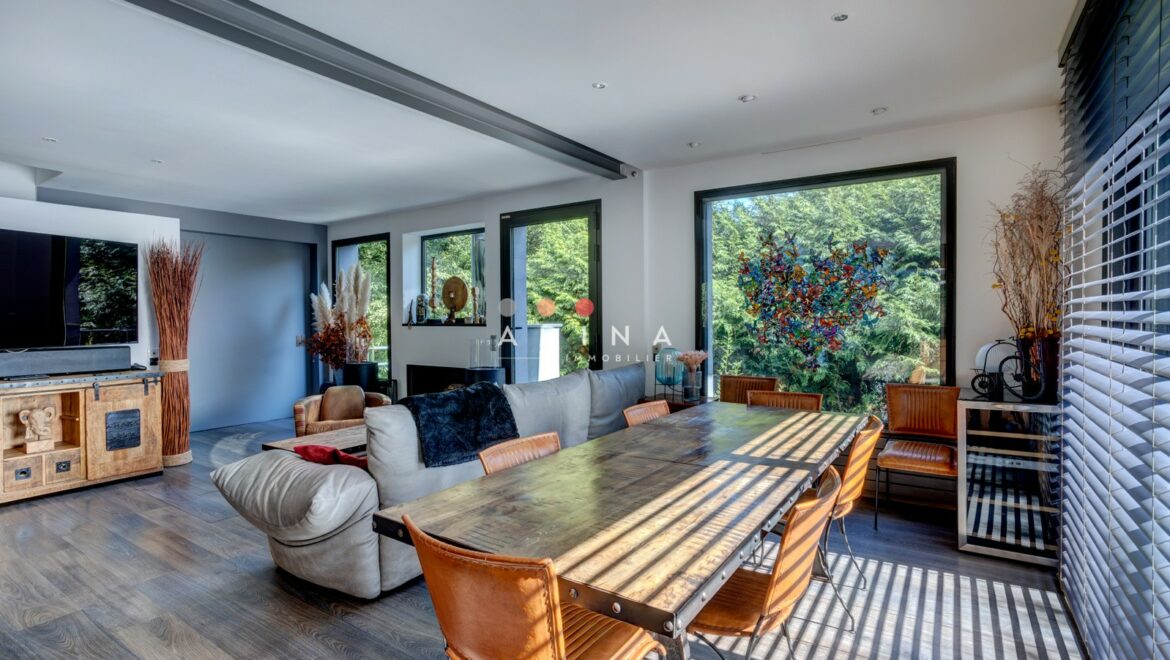 Salle à manger lumineuse avec grandes fenêtres et mobilier moderne.