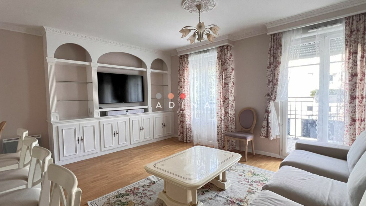 Salon lumineux avec décoration classique, meubles blancs et rideaux floraux.