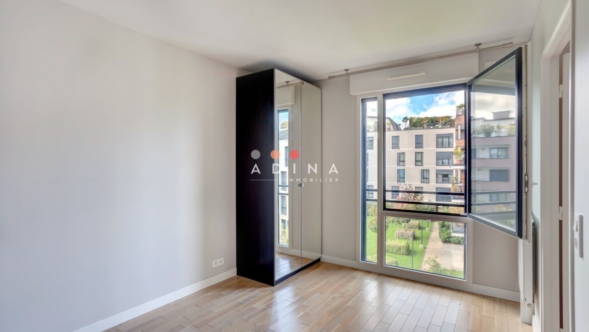 Chambre vide avec fenêtre ouverte et vue sur jardin.