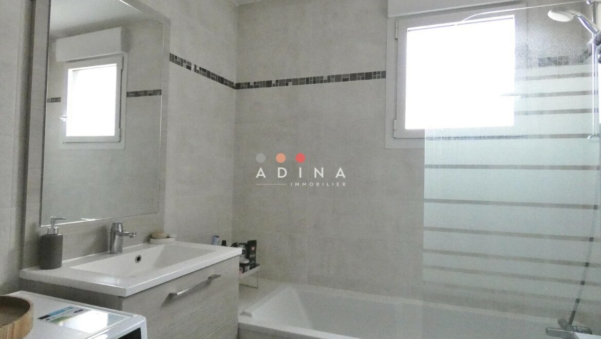 Salle de bains moderne avec baignoire et fenêtre.