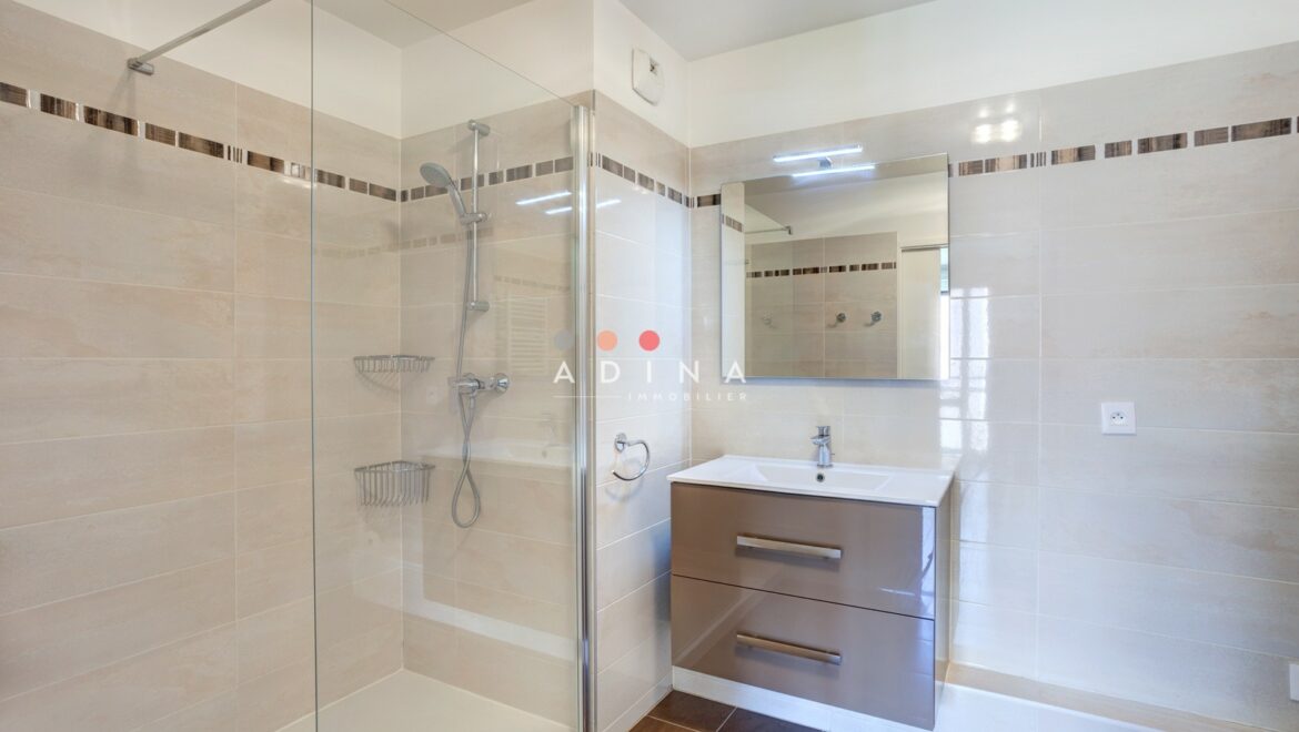 Salle de bain moderne avec douche à l'italienne et lavabo.