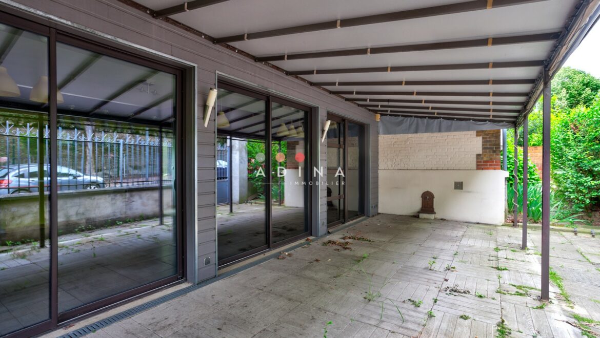 Terrasse couverte avec grandes baies vitrées.