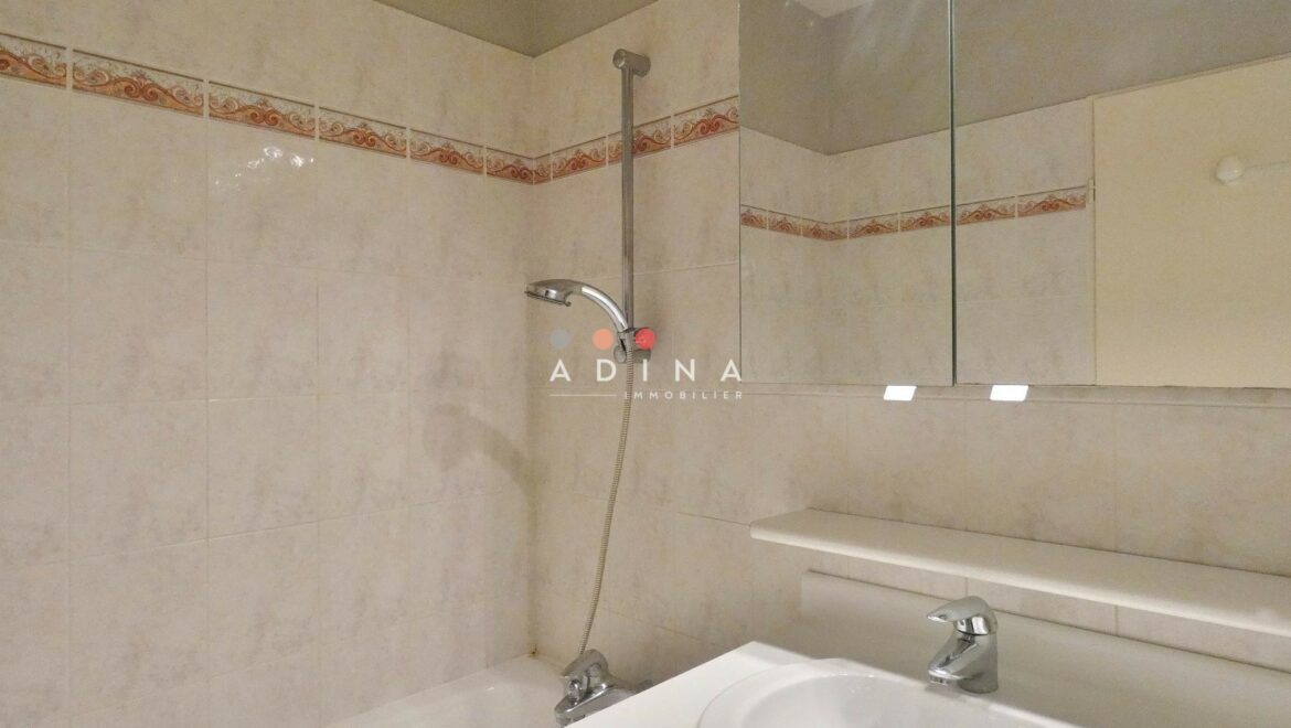 Salle de bains avec carrelage à motifs et miroir.